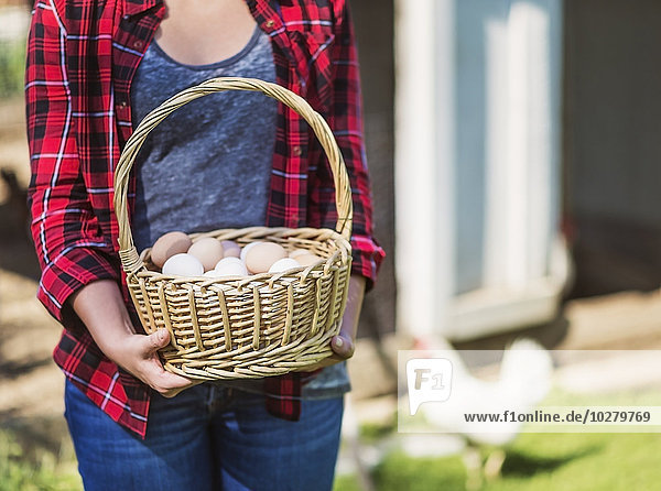 Female farmer carrying basket with eggs