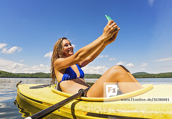 Junge Frau macht Selfie im Kajak auf dem See