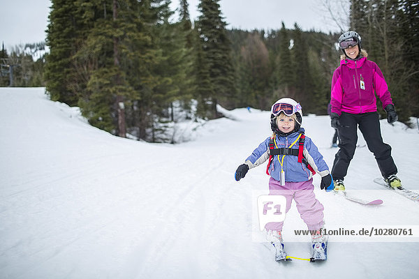 Little girl (2-3) learning skiing with mother
