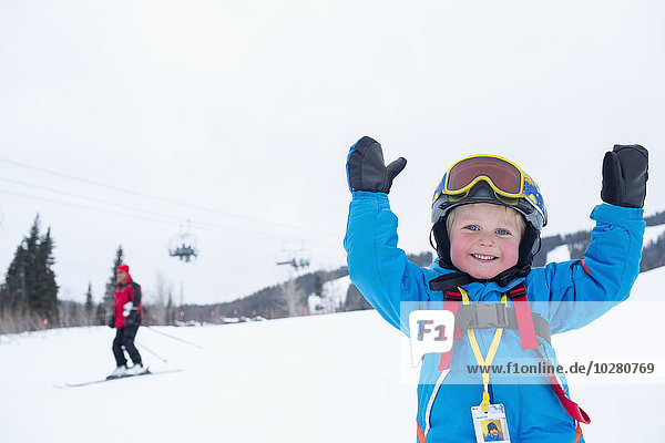 Lächelnder kleiner Junge (5) im Skianzug in den Bergen
