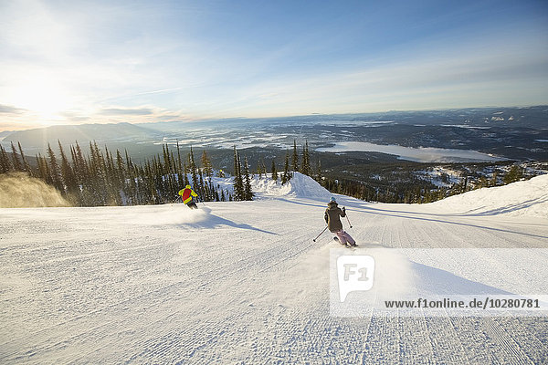 Two people on ski slope at sunlight