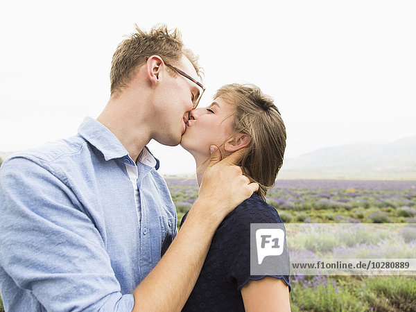 Junges Paar  das sich küsst  mit Feld im Hintergrund