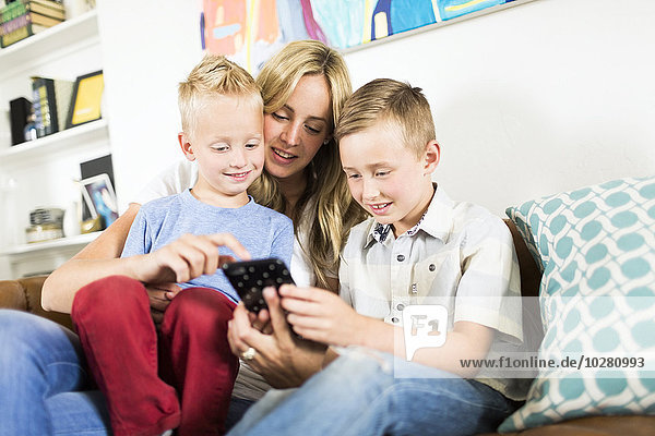 Mutter mit Kindern (4-5  6-7) benutzt Smartphone auf dem Sofa