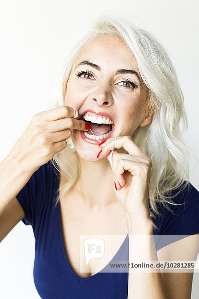 Studioaufnahme einer Frau mit Zahnseide