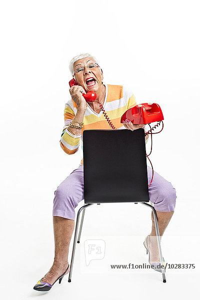 Ältere Frau sitzt auf einem Stuhl und telefoniert