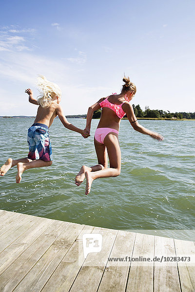 Junge und Mädchen springen ins Wasser