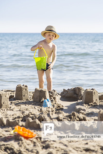 Junge am Strand baut Sandburgen