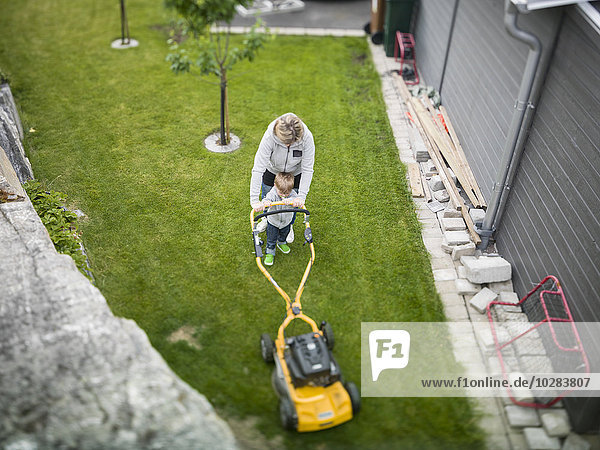 Woman with son mowing lawn
