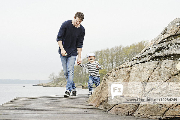 Vater mit Sohn beim Spaziergang auf dem Bootssteg