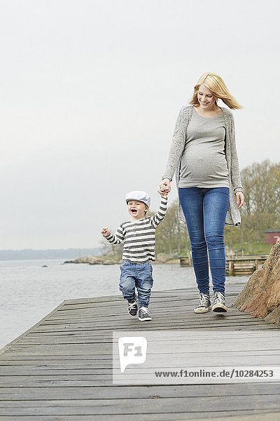 Frau mit Sohn spaziert auf Steg