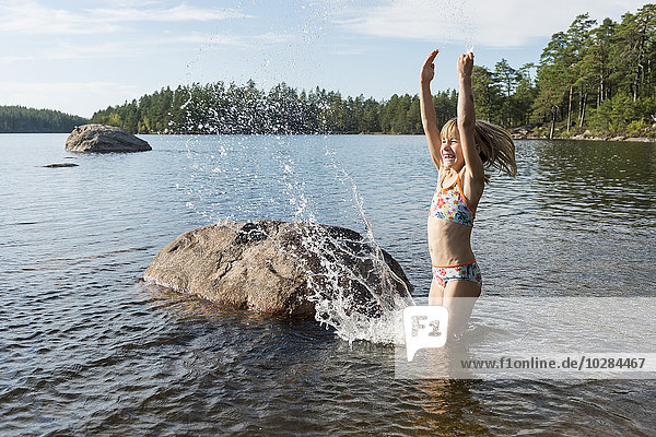 Happy girl splashing water in lake