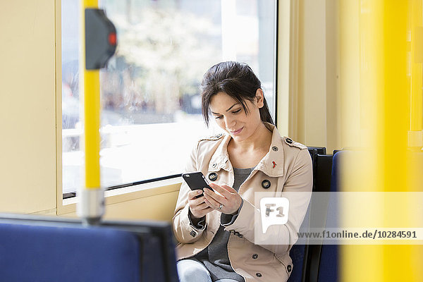 Frau benutzt Mobiltelefon in der Straßenbahn