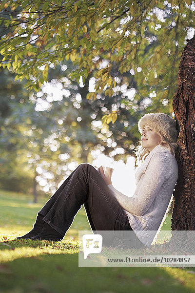 Junge Frau sitzt unter einem Baum