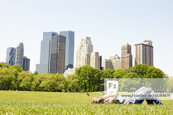Woman in Central Park with Manhattan skyline  New York City  USA