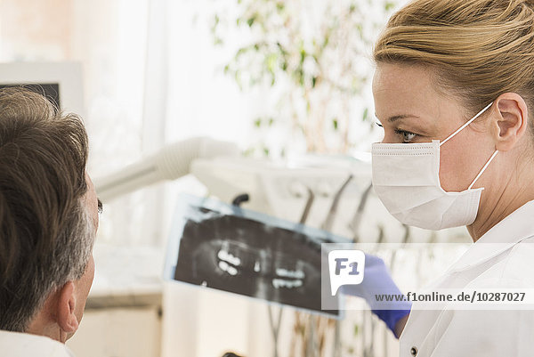 Zahnärztin bei der Besprechung eines Röntgenberichts mit einem Patienten  München  Bayern  Deutschland