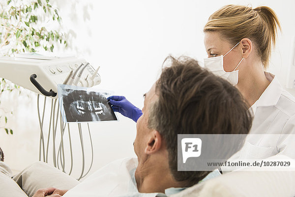 Female dentist discussing an X-ray report with patient  Munich  Bavaria  Germany