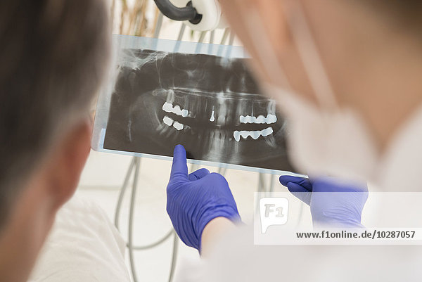 Zahnarzt bei der Besprechung eines Röntgenberichts mit einem Patienten  München  Bayern  Deutschland
