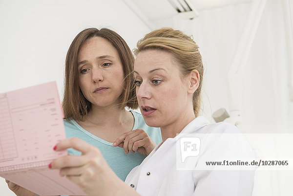 Female dentist discussing the index card of a patient with dental assistant  Munich  Bavaria  Germany