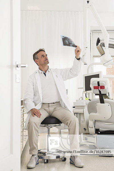 Männlicher Zahnarzt bei der Untersuchung eines Röntgenberichts  München  Bayern  Deutschland