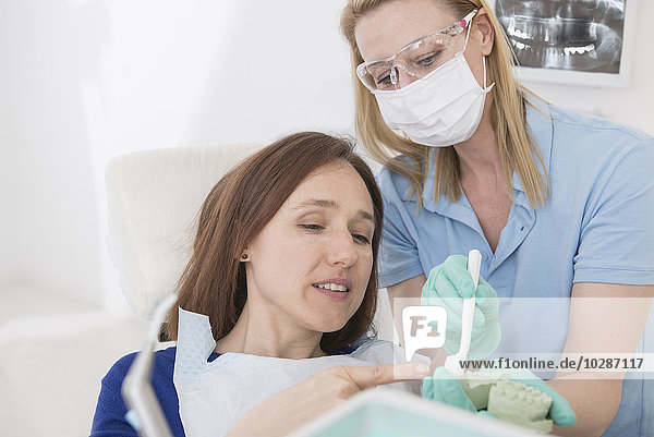 Dental assistant explaining a patient how to brush teeth  Munich  Bavaria  Germany