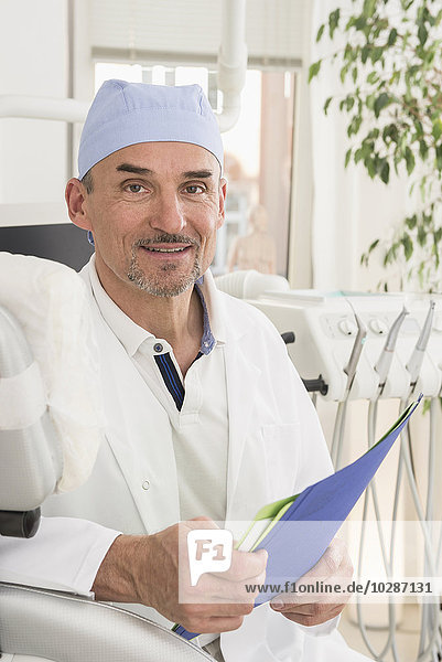 Portrait of dentist holding file and smiling  Munich  Bavaria  Germany