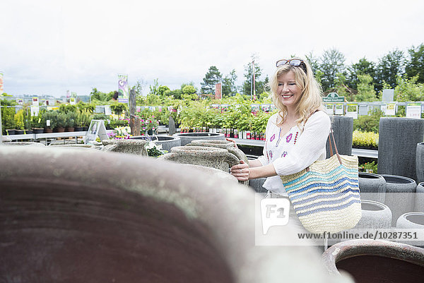 Mature woman choosing urn in greenhouse Augsburg Bavaria Germany