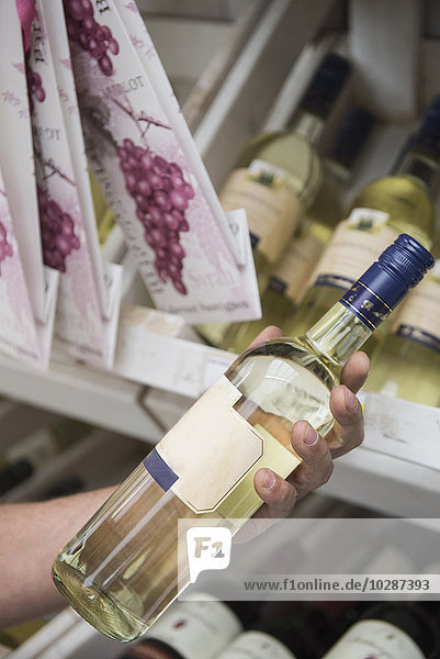 Kunde liest Etikett auf einer Weinflasche im Supermarkt  Augsburg  Bayern  Deutschland