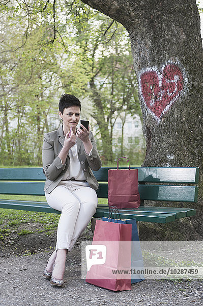 Ältere Frau trägt Lippenstift für ihre Verabredung im Park auf  Bayern  Deutschland
