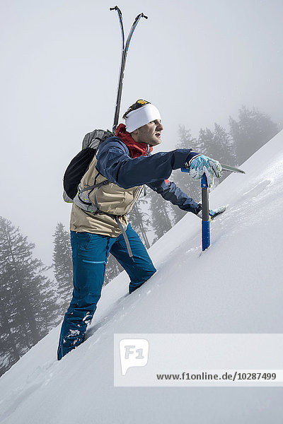 Male mountain climber going up snowy slope with pick axe  Zell Am See  Austria
