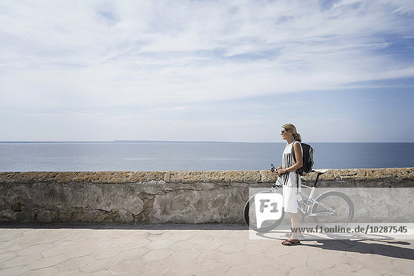 Seitenprofil einer reifen Frau mit Mountainbike an der Hafenmauer  Gallipoli  Apulien  Italien