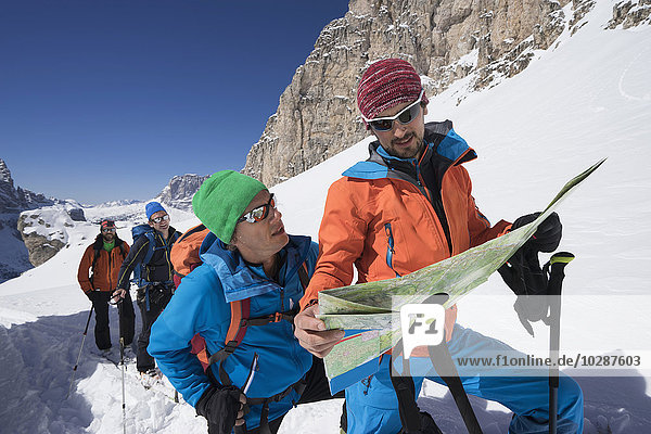 Ski mountaineers reading map while climbing on snowy mountain  Val Gardena  Trentino-Alto Adige  Italy