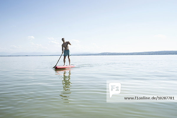 Mature man paddleboarding in the lake  Bavaria  Germany