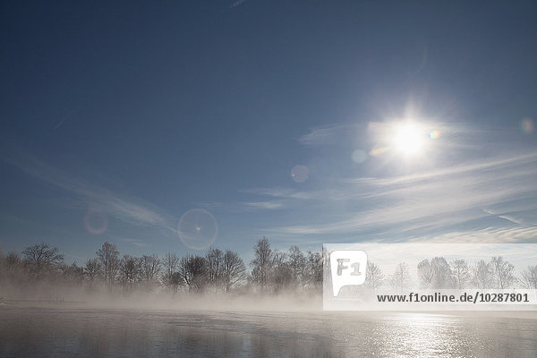 Sun shining over lake in winter  Eichenau  Fürstenfeldbruck  Bavaria  Germany