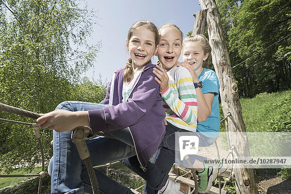 Girls sitting on suspension bridge in playground  Munich  Bavaria  Germany