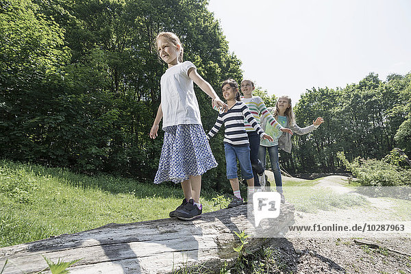 Mädchen balancieren auf einem Baumstamm auf einem Spielplatz  München  Bayern  Deutschland