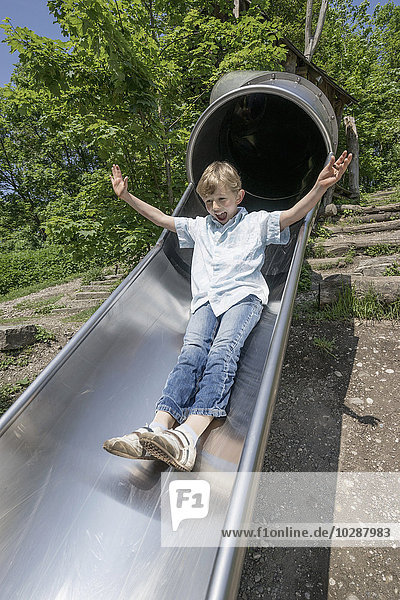 Junge rutscht auf einer Rutsche auf einem Spielplatz  München  Bayern  Deutschland