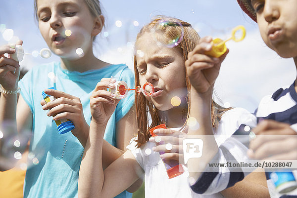 Mädchen blasen Seifenblasen mit Seifenblasenstäben  Bayern  Deutschland
