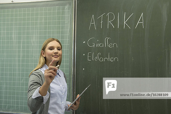 Lehrer schreibt an Tafel im Klassenzimmer  München  Bayern  Deutschland