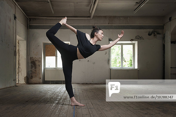 Mittlere erwachsene Frau beim Üben der Natarajasana-Pose im Yogastudio  München  Bayern  Deutschland