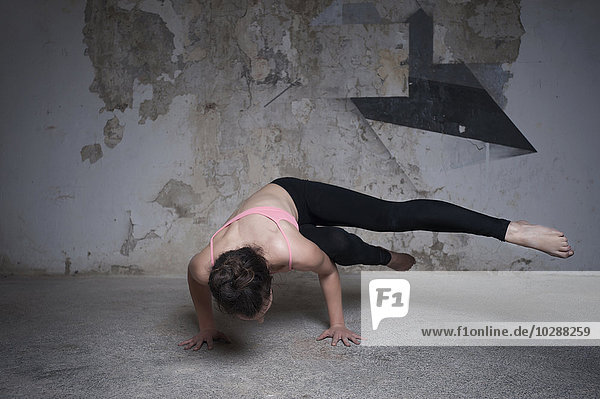 Mittlere erwachsene Frau beim Üben der Parsva-Bakasana-Pose im Yogastudio  München  Bayern  Deutschland