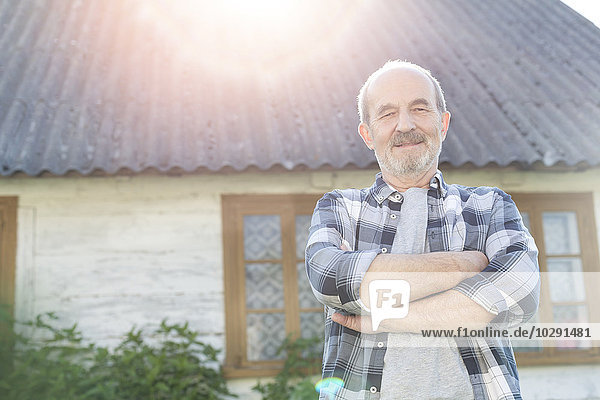 Porträt selbstbewusster Senior-Bauer vor dem Bauernhaus