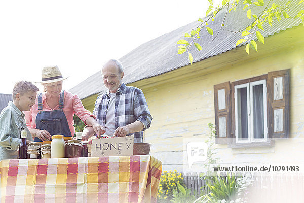 Großeltern und Enkel beim Honigverkauf