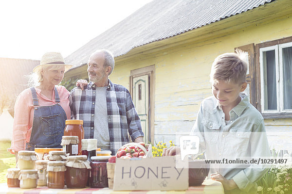 Großeltern und Enkel beim Honigverkauf