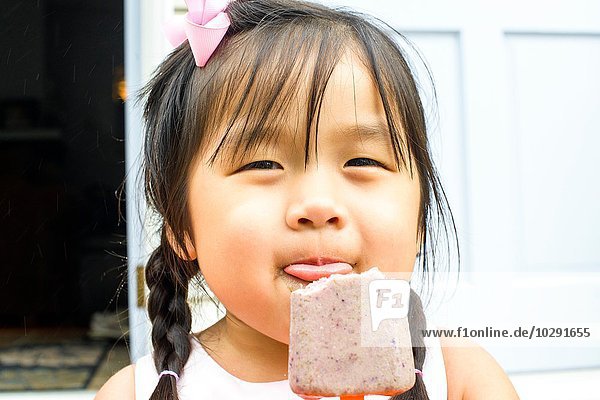 Porträt eines jungen Mädchens  das Eis am Stiel isst.