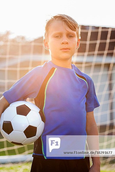 Porträt eines jungen Fußballspielers  der Fußball vor dem Tor hält.