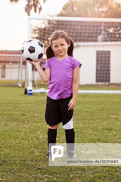 Porträt einer Fußballerin  die den Fußball auf dem Übungsplatz hochhält.