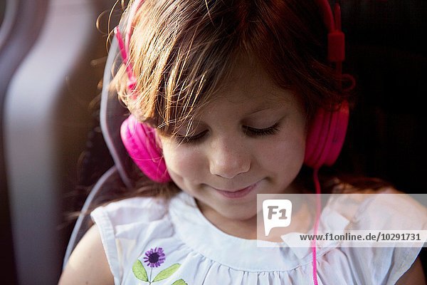 Nahaufnahme eines Mädchens mit rosa Kopfhörern im Auto