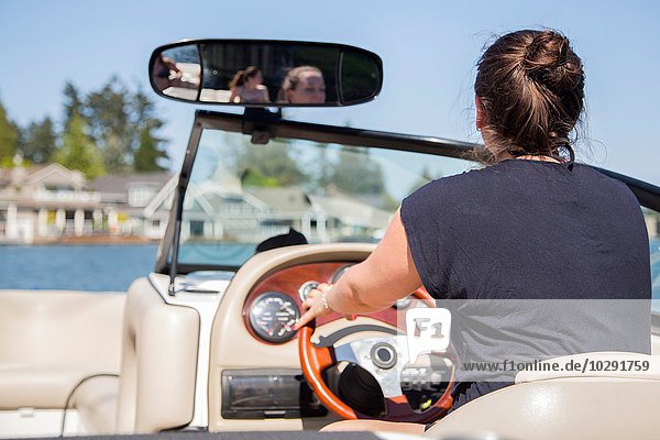 Rear view of young woman driving motor boat  Lake Oswego  Oregon  USA