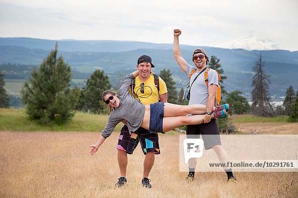 Small group of hikers  fooling around  two men holding woman up  laughing  celebrating