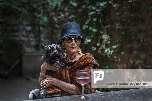 Fashionable senior woman with dog in garden